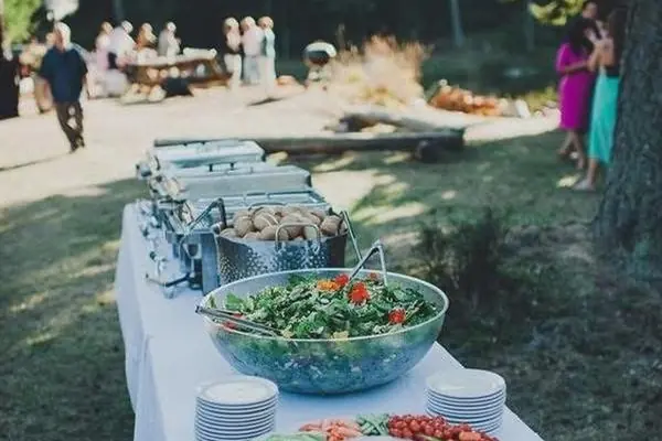 A buffet table with salads and platters set for a garden gathering.